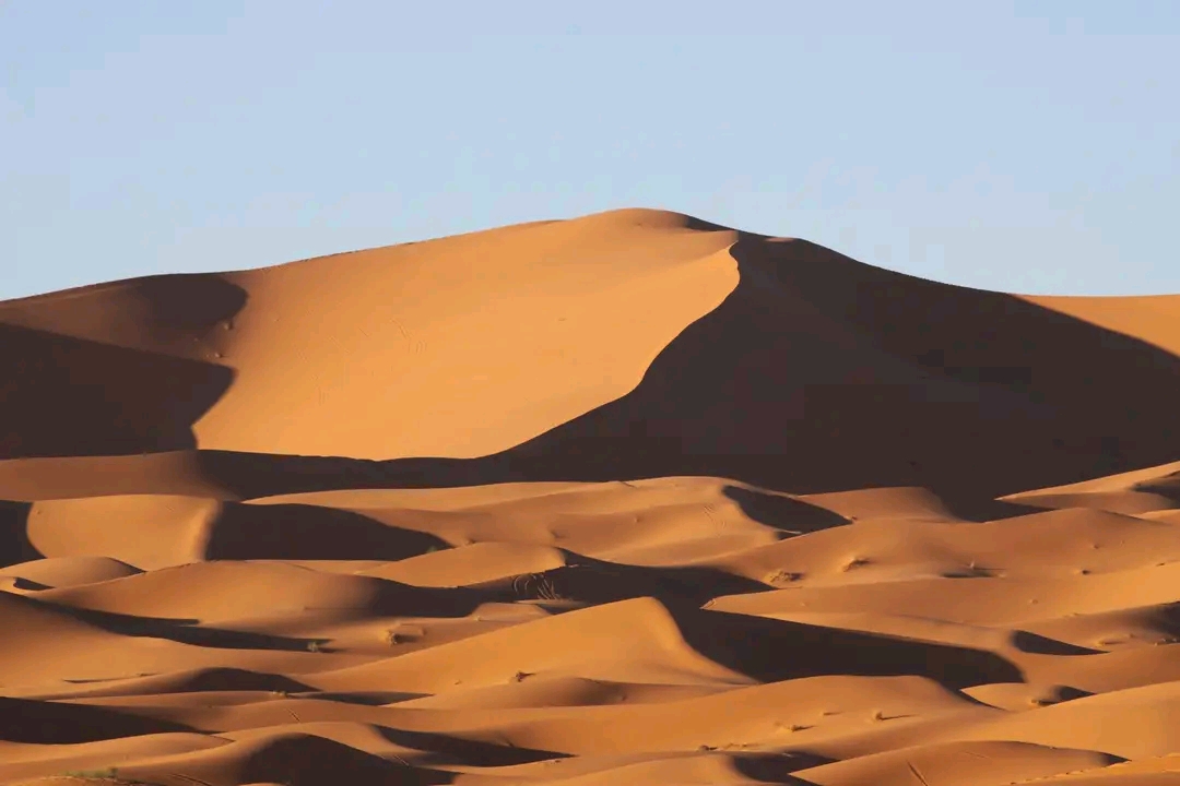 Golden sand dunes of the Sahara Desert in Merzouga, Morocco, with camel trekking, luxury desert camps, and breathtaking sunset views.